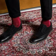 Czerwone skarpety do garnituru? Tak! Eleganckie czarne buty i bordowy dywan tworzą stylowy zestaw.