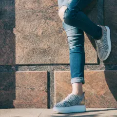 Nogawki jeansów podwinięte na kostkach, odsłaniające modne sneakersy. Idealny sposób, jak podwinąć spodnie na lato.