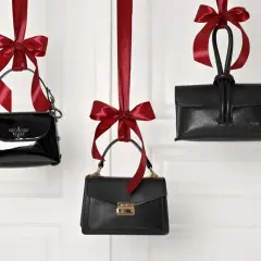 Różne rodzaje torebek wiszą na czerwonych wstążkach. Eleganckie, czarne, z ozdobami i złotymi elementami.