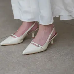 Eleganckie, kremowe stopy w szpilkach z paskiem wokół kostki, idealne do letniej sukienki.
