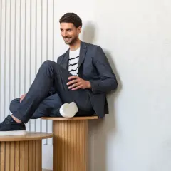 Mężczyzna w granatowym garniturze i t-shircie w paski, prezentujący styl smart casual.