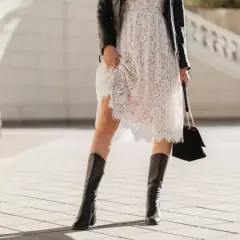 Kowbojki do sukienki: biała koronkowa sukienka, czarna ramoneska i elegancka torebka tworzą stylowy zestaw.