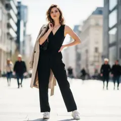 Elegancki czarny kombinezon i białe sneakersy – idealne połączenie, które odpowiada na pytanie, jakie buty do kombinezonu. Kobieta w miejskiej scenerii.