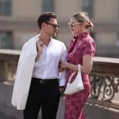 Elegancka para, inspiracja, jak się ubrać na poprawiny. Ona w różowej sukience w róże, on w białej koszuli i czarnych spodniach.