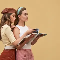 Dwie kobiety w stylizacjach z lat 60. moda damska, jedna w brązowym beretku, druga czyta magazyn.