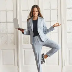 Kobieta w jasnoniebieskim garniturze, trzymająca laptopa i w pozie jogi. Idealny styl casual damski do pracy i relaksu.