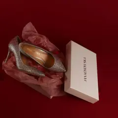 Srebrne, błyszczące szpilki w pudełku. Idealne buty na studniówkę, które dodadzą blasku każdej stylizacji.