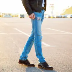 Mężczyzna w skórzanej kurtce i podartych jeansach, idealnie dobrane buty do kurtki skórzanej.