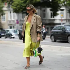 Elegancka sukienka dla figury jabłka w kolorze limonki, zestawiona z beżową marynarką i stylową torebką.