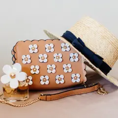 Brązowa torebka z kwiatkami, słomkowy kapelusz i perfumy Daisy. Idealny zestaw na letnie dni.