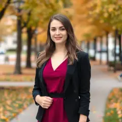 Elegancka kobieta w bordowej sukience i czarnym żakiecie, idealny zestaw na jesienny spacer.