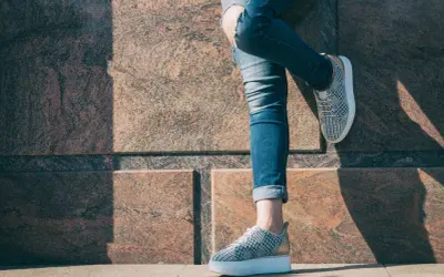 Nogawki jeansów podwinięte na kostkach, odsłaniające modne sneakersy. Idealny sposób, jak podwinąć spodnie na lato.