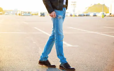 Mężczyzna w skórzanej kurtce i podartych jeansach, idealnie dobrane buty do kurtki skórzanej.