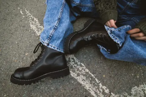 Czarne, sznurowane buty na grubej podeszwie, jeansy i sweter w zielone wzory – idealny zestaw w rock style.