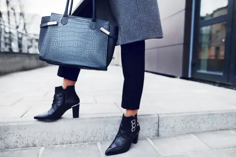 Eleganckie stylizacje z botkami na obcasie: czarne, skórzane botki z klamrami i metalowymi detalami, do tego szara marynarka i torebka z fakturą skóry krokodyla.