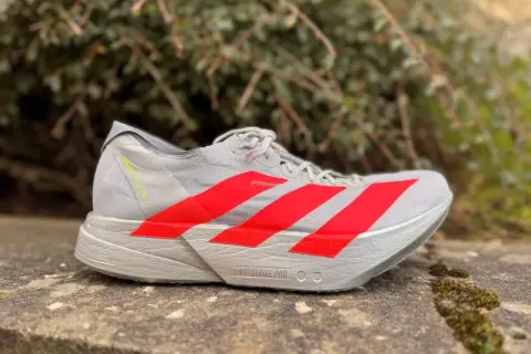 Szary but biegowy adidas adios pro 4 z czerwonymi paskami, gotowy na szybkie trasy.