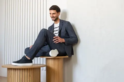 Mężczyzna w granatowym garniturze i t-shircie w paski, prezentujący styl smart casual.