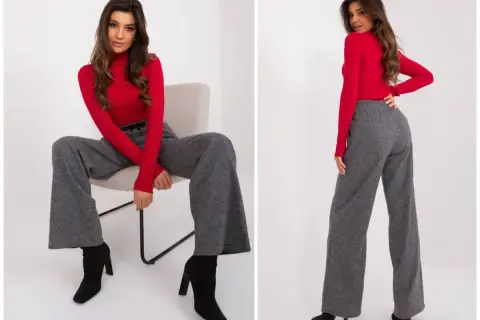 Modelka w czerwonym golfie i szarych, szerokich spodniach na grube uda, które dodają elegancji.