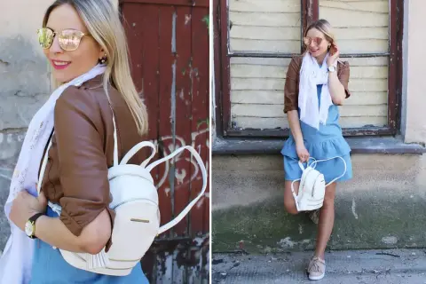 Kobieca stylizacja: jeansowa sukienka, brązowa ramoneska, biały plecaczek i beżowe sneakersy. Idealne buty do jeansowej sukienki na co dzień.