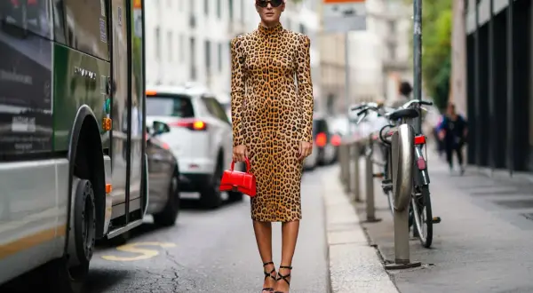 Elegancka kobieta w sukience w panterkę i czarnych sandałkach na obcasie. Idealne buty do sukienki w panterkę to te, które podkreślą jej charakter.