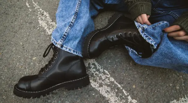 Czarne, sznurowane buty na grubej podeszwie, jeansy i sweter w zielone wzory – idealny zestaw w rock style.