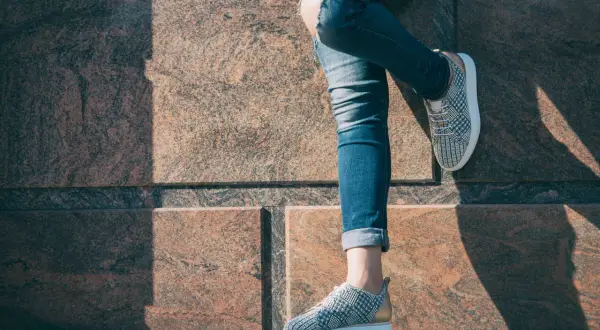 Nogawki jeansów podwinięte na kostkach, odsłaniające modne sneakersy. Idealny sposób, jak podwinąć spodnie na lato.