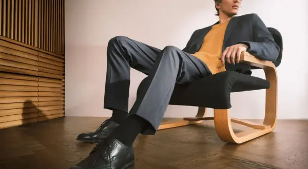 Mężczyzna w granatowej marynarce i musztardowym swetrze, spodnie i eleganckie buty tworzą stylowy ubiór casual.