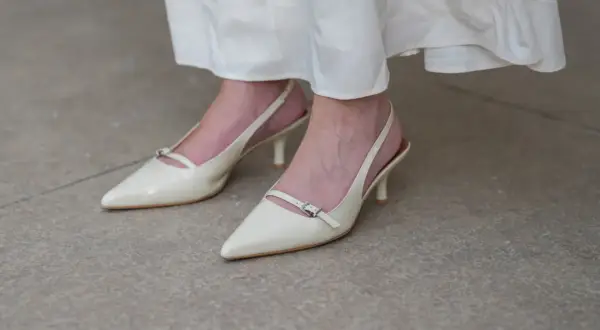 Eleganckie, kremowe stopy w szpilkach z paskiem wokół kostki, idealne do letniej sukienki.