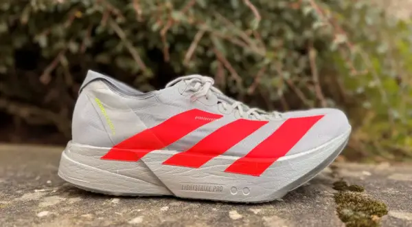 Szary but biegowy adidas adios pro 4 z czerwonymi paskami, gotowy na szybkie trasy.