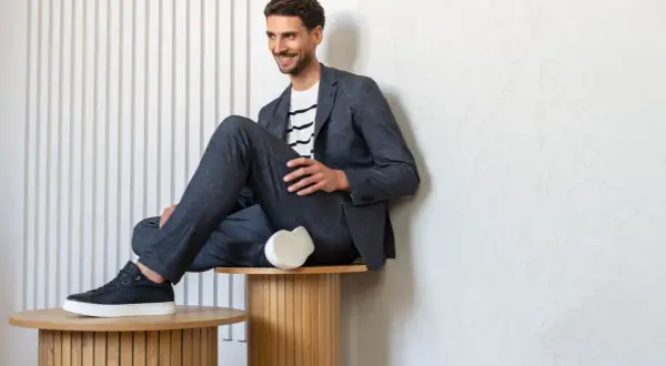 Mężczyzna w granatowym garniturze i t-shircie w paski, prezentujący styl smart casual.