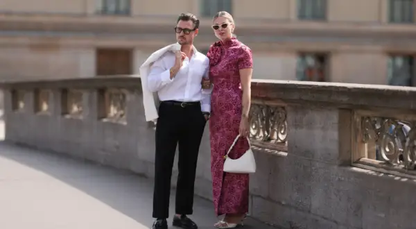 Elegancka para, on w białej koszuli i czarnych spodniach, ona w sukni z różami. Idealne inspiracje, jakie buty do teatru wybrać na wieczorne wyjście.