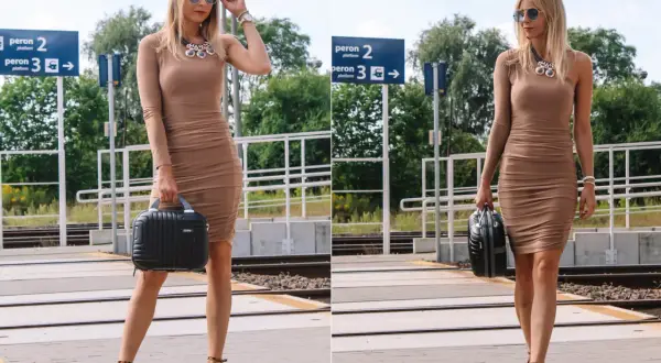 Jaka torebka do beżowej sukienki? Elegancka, czarna, mała walizeczka idealnie pasuje do tej stylizacji na dworcu.