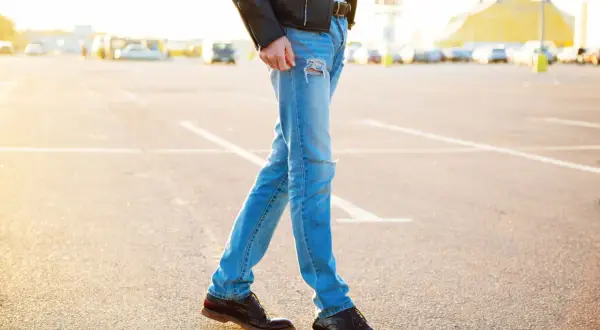 Mężczyzna w skórzanej kurtce i podartych jeansach, idealnie dobrane buty do kurtki skórzanej.