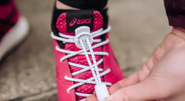 Różowe buty Asics z białymi sznurówkami wstążkami, które ułatwiają zakładanie.