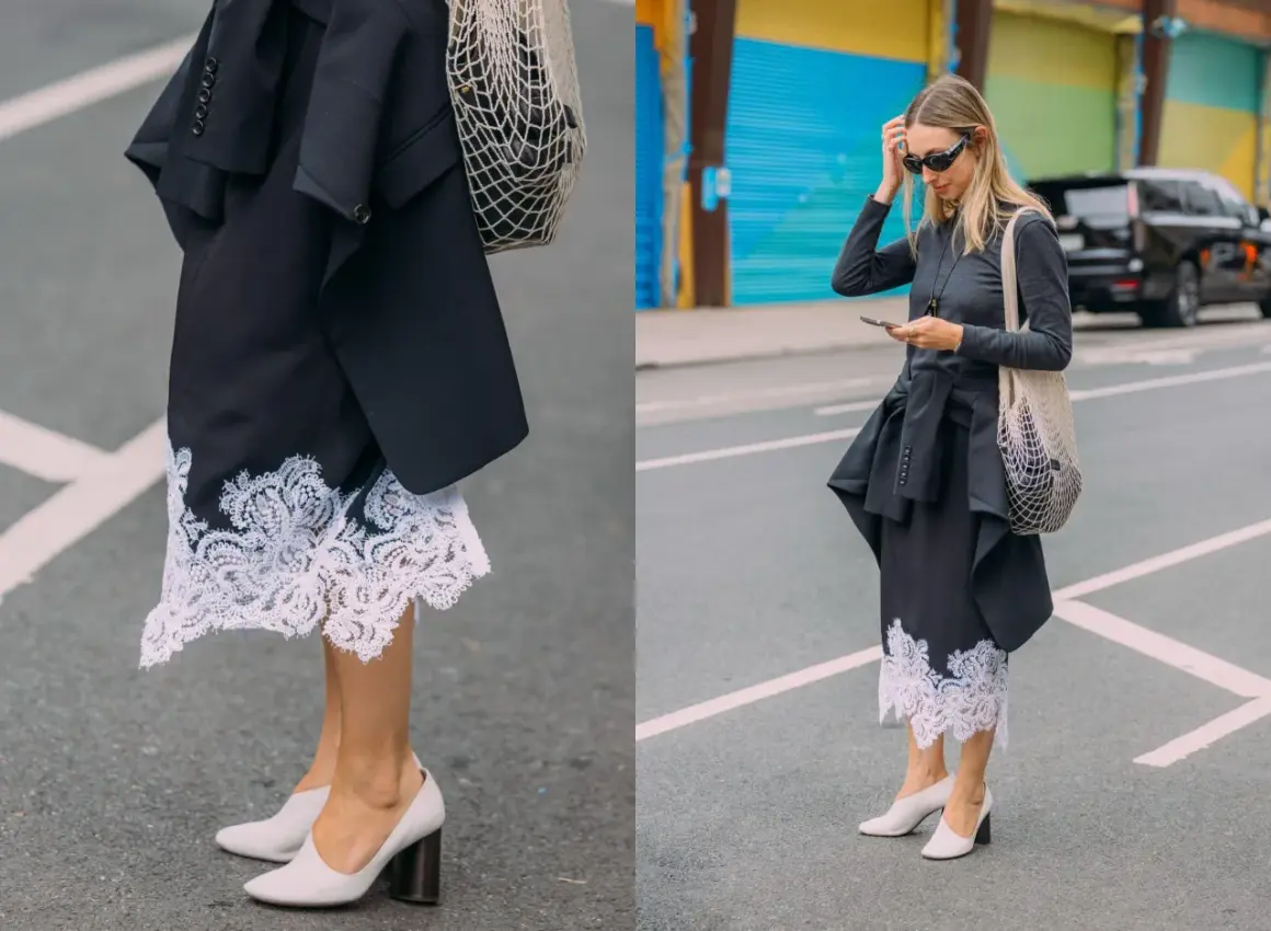 Elegancka koronkowa spódnica stylizacje z czarną marynarką i siatkową torbą. Kobieta w okularach przeciwsłonecznych i szarej bluzce z długim rękawem.