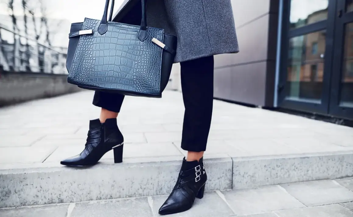 Eleganckie stylizacje z botkami na obcasie: czarne, skórzane botki z klamrami i metalowymi detalami, do tego szara marynarka i torebka z fakturą skóry krokodyla.