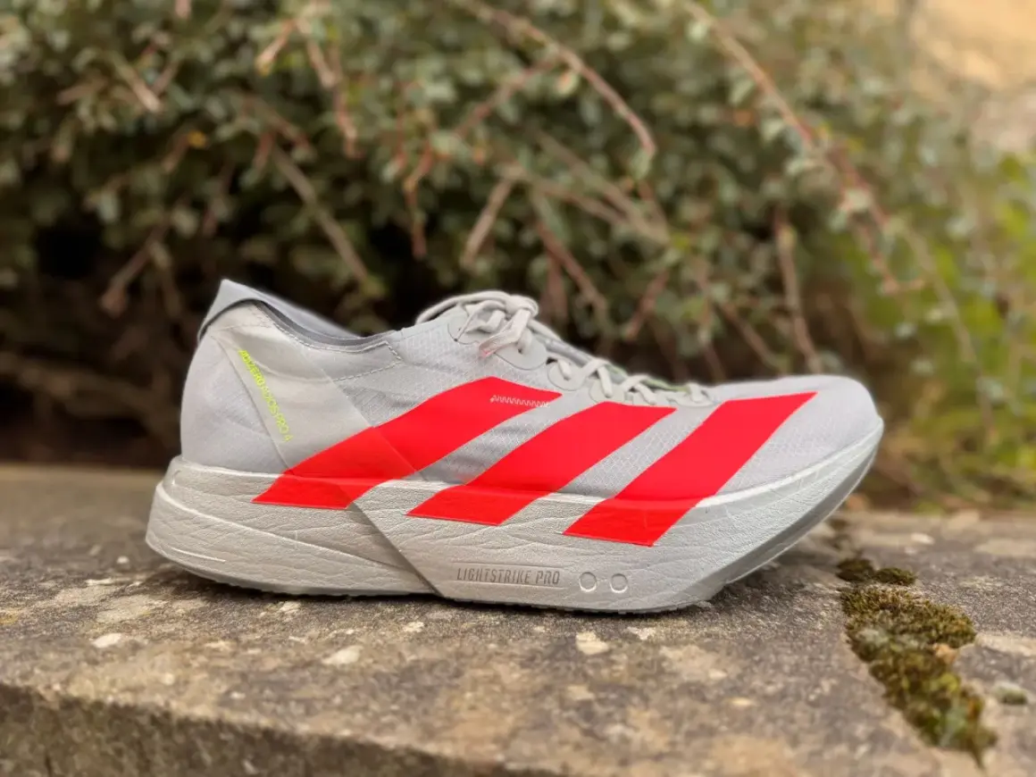 Szary but biegowy adidas adios pro 4 z czerwonymi paskami, gotowy na szybkie trasy.