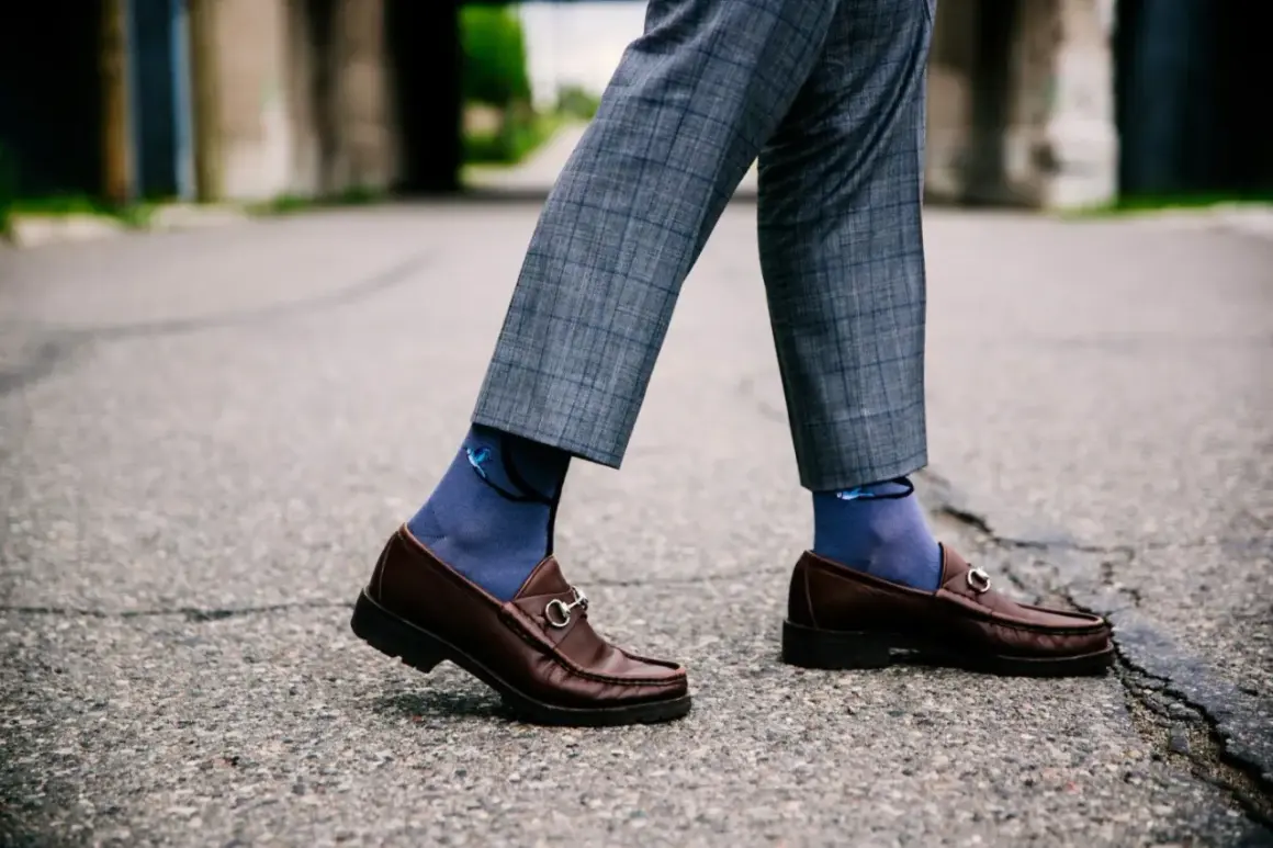 Eleganckie skarpetki do mokasynów w kolorze granatowym z motywem ptaków, idealnie komponują się z szarymi spodniami w kratę.