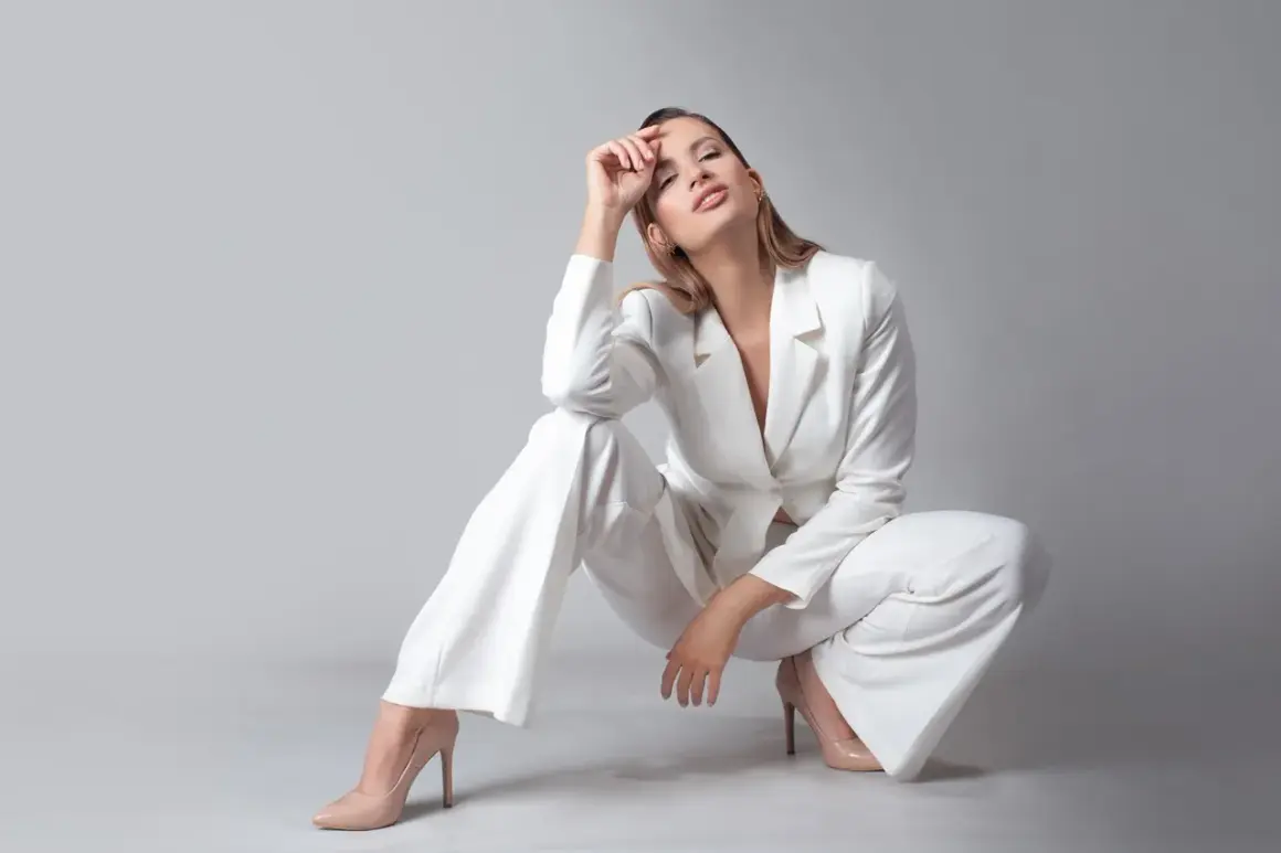 Elegancka kobieta w białym garniturze i cielistych szpilkach. Idealne buty do garnituru damskiego, które podkreślają styl.