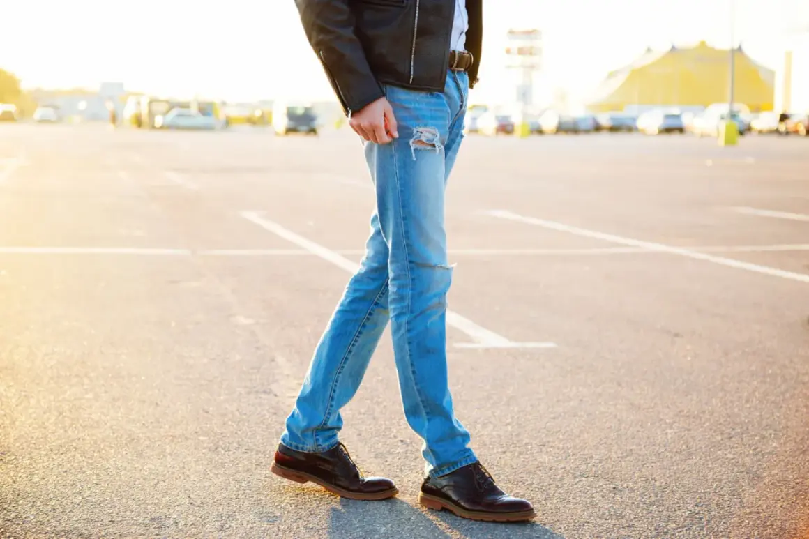Mężczyzna w skórzanej kurtce i podartych jeansach, idealnie dobrane buty do kurtki skórzanej.