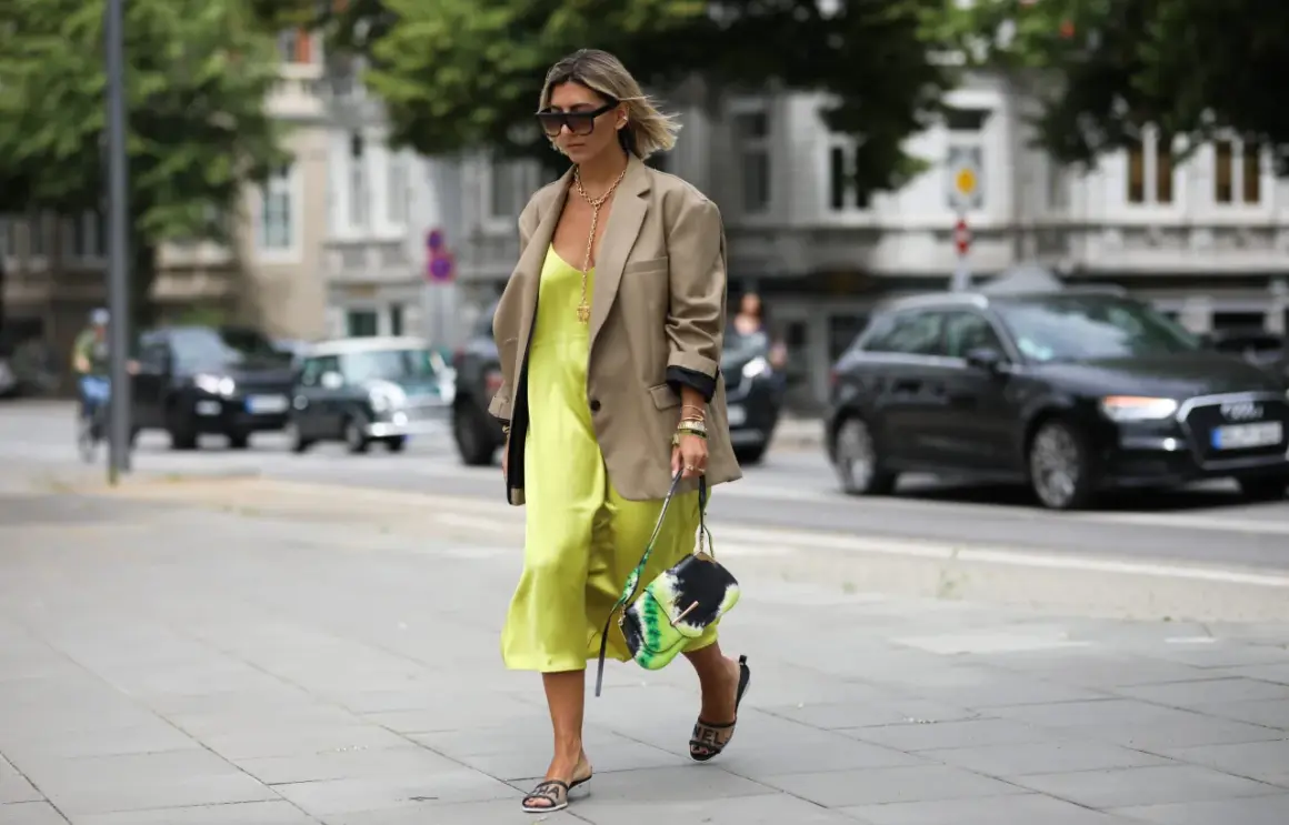 Elegancka sukienka dla figury jabłka w kolorze limonki, zestawiona z beżową marynarką i stylową torebką.