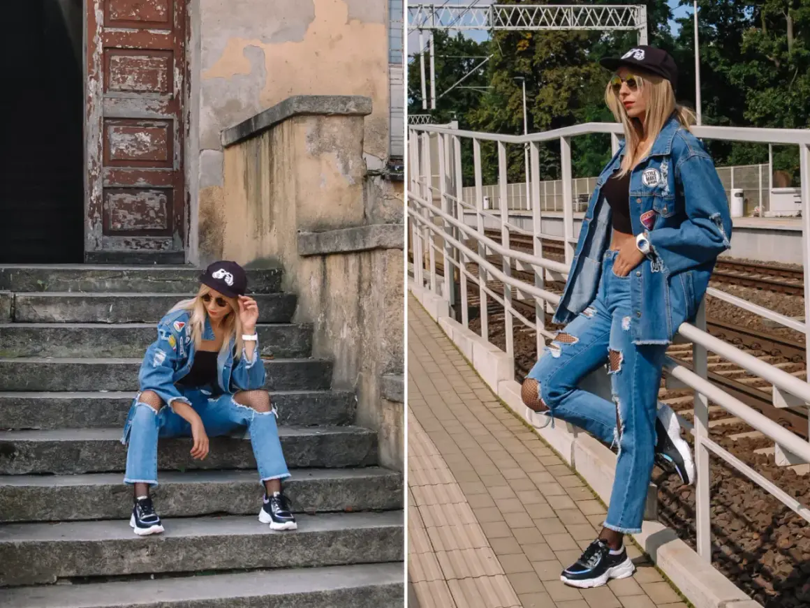 Stylowa kobieta w jeansach boyfriend i kurtce denim, z naszywkami i przetarciami, na tle schodów i torów kolejowych.