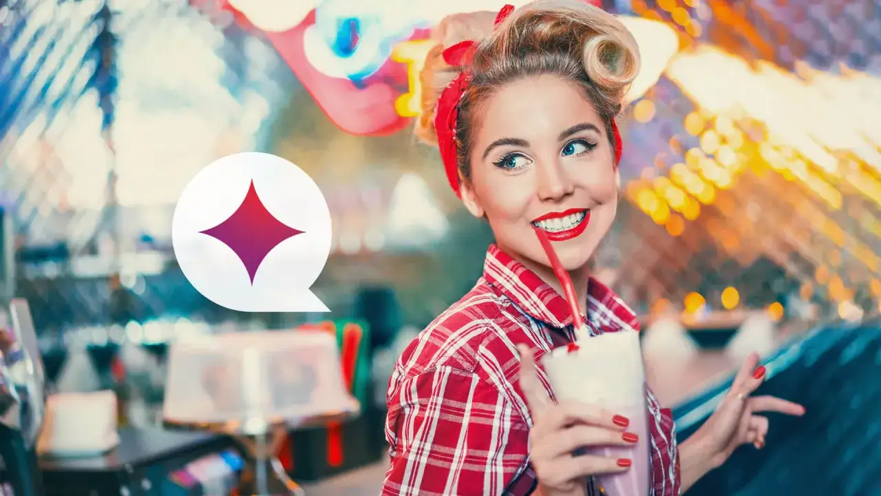 Uśmiechnięta dziewczyna w stylu pin-up girl z burzą blond loków i czerwoną bandaną pije mleczny koktajl.
