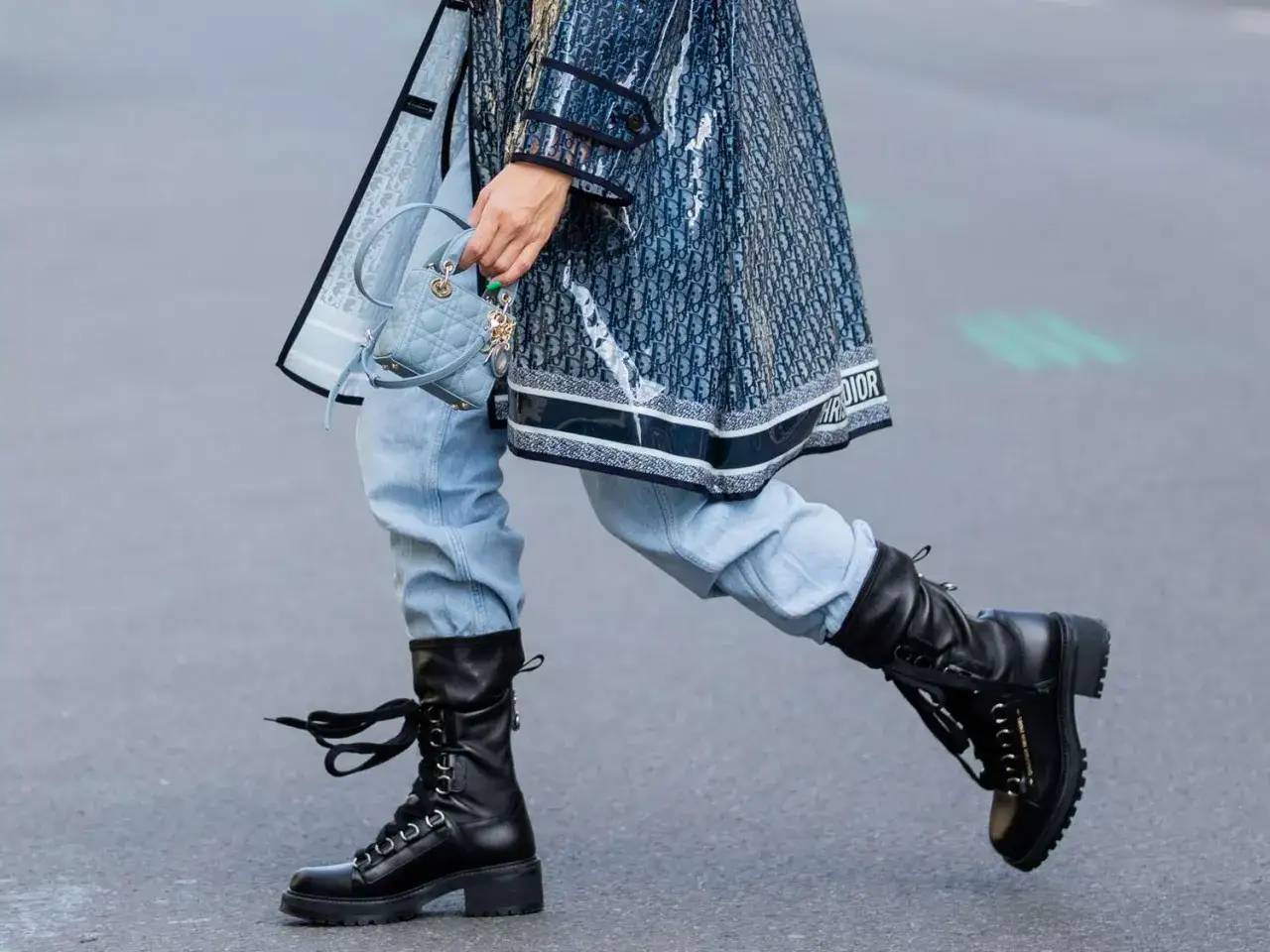 Stylizacja w stylu grunge: czarne, sznurowane botki na grubej podeszwie, jasne jeansy i transparentny płaszcz z monogramem Dior.