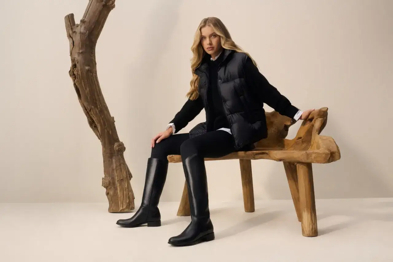Eleganckie kozaki na bardzo szeroką łydkę, idealne do jesiennych stylizacji. Modelka w czarnym puchowym bezrękawniku i legginsach.