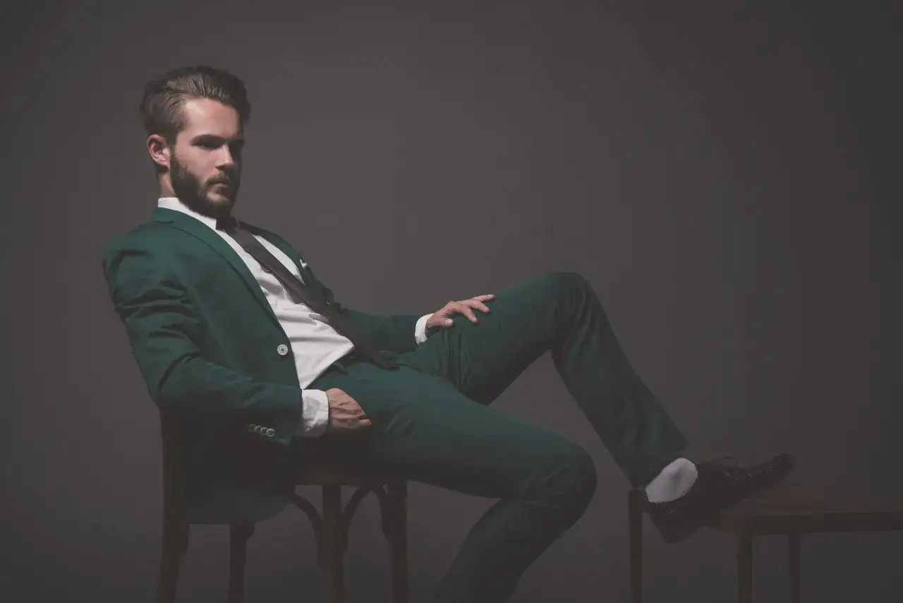 Elegancki mężczyzna w zielonym garniturze i czarnych butach. Idealne połączenie, jeśli zastanawiasz się, jakie buty do zielonego garnituru wybrać.