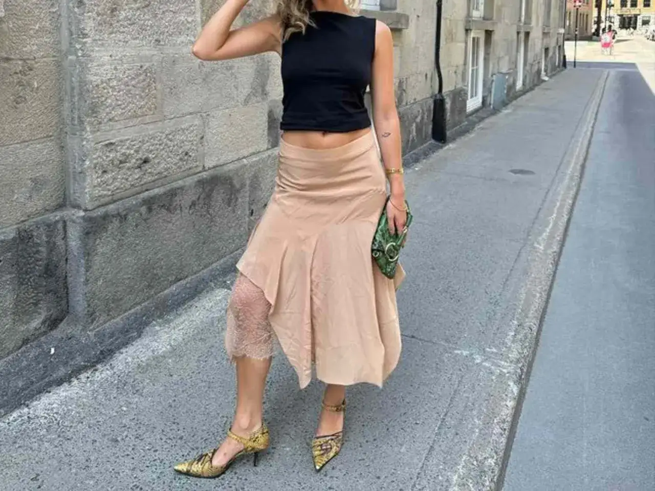 Elegancka satynowa spódnica w beżowym kolorze, zestawiona z czarnym topem i wzorzystymi szpilkami. Stylowe satynowa spódnica stylizacje.