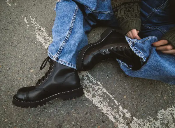 Czarne, sznurowane buty na grubej podeszwie, jeansy i sweter w zielone wzory – idealny zestaw w rock style.