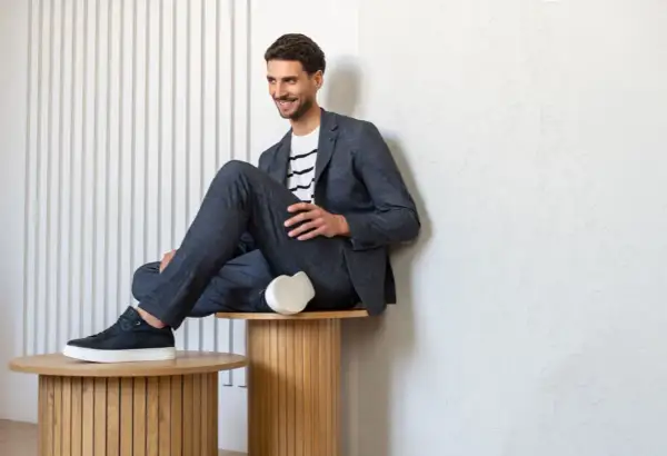 Mężczyzna w granatowym garniturze i t-shircie w paski, prezentujący styl smart casual.