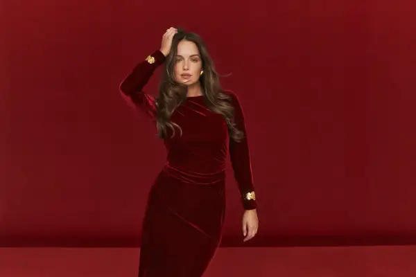 Elegancka kobieta w czerwonej welurowej sukience z złotymi zdobieniami. Idealne buty do welurowej sukienki podkreślą jej styl.